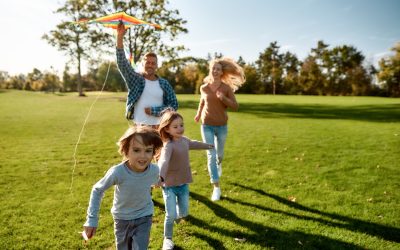 a young boy flying a kite while standing on a lush green field