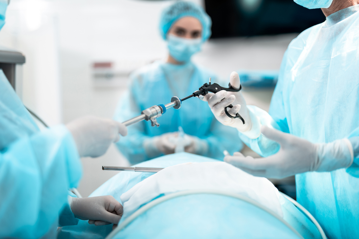 Three doctors in an operating room performing laparoscopic surgery, a common form of minimally invasive surgery. 