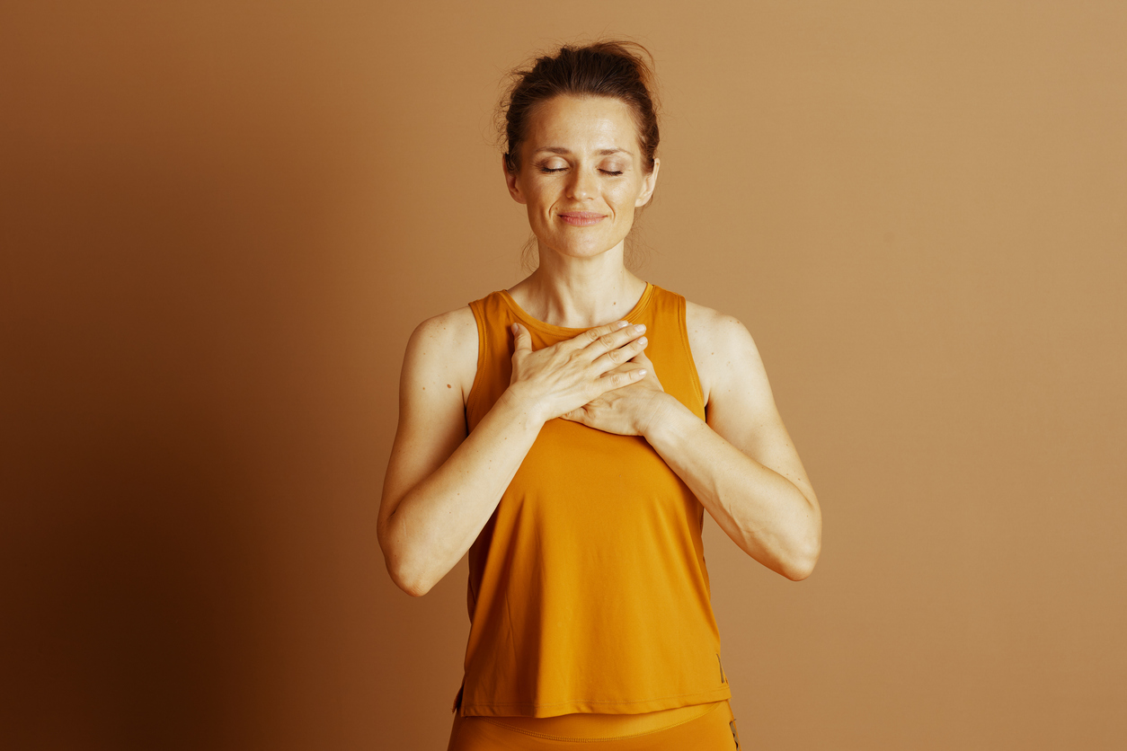 A woman holding her hands to her chest in thankfulness after a workout, symbolizing gratitude in her weight loss journey.
