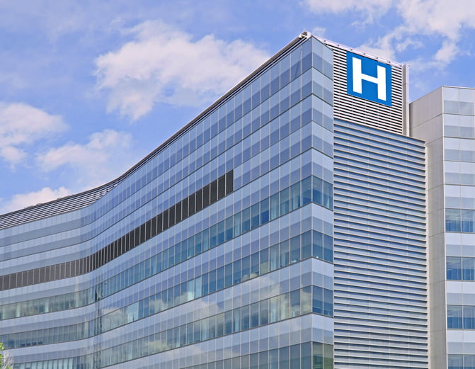A high-rise urban hospital building with a large “H” on the side with a cloudy blue sky in the background. Home to a bariatric surgical center.